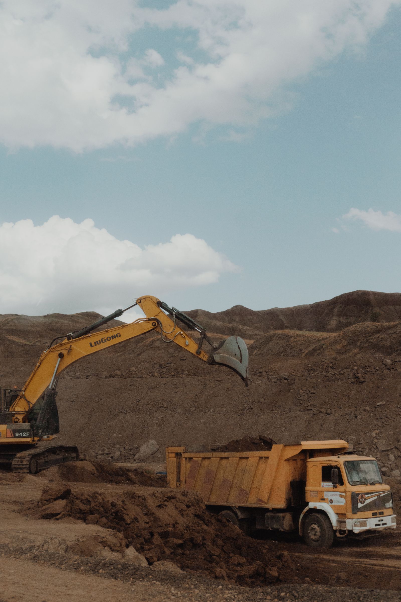 Excavator loading a dump truck in a mining landscape
